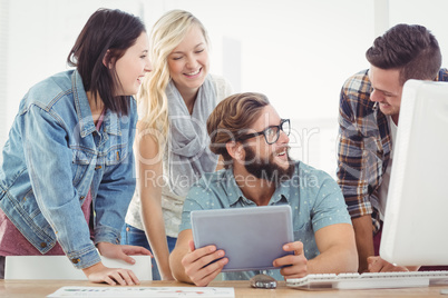 Happy business people using digital tablet at computer desk