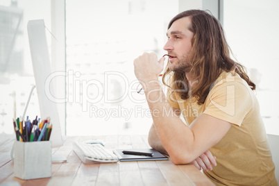 Thoughtful hipster at computer desk