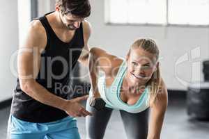 Sporty woman using dumbbells with personal trainor