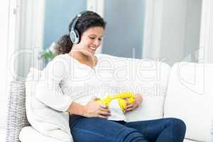 Happy woman with headphones on belly and head