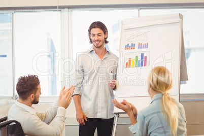 Business people clapping for male colleague