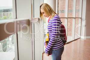 Sad female student by window in college