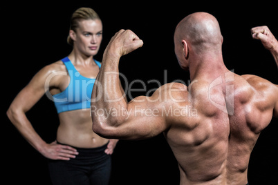 Bald muscular man flexing muscles in front of trainer