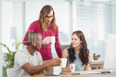 Business people holding coffee cups while working at computer de