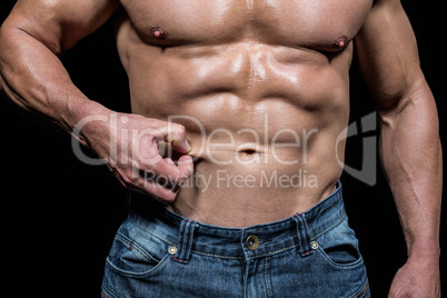 Midsection of muscular man holding skin