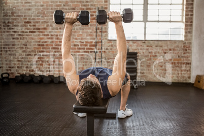 Man lifting dumbbells while lying on exercise bench Man lifting dumbbells while lying on exercise bench