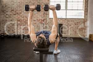 Man lifting dumbbells while lying on exercise bench