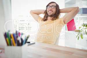 Happy hipster relaxing at desk in office