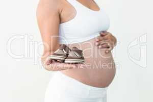 Pregnant woman showing baby shoes