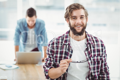 Portrait of smiling businessman holding eyeglasses