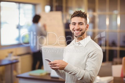 Portrait of smiling businessman texting on phone