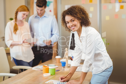 Businesswoman standing by table with colleagues