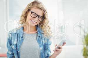 Portrait of smiling woman wearing eyeglasses while holding smart