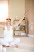 Full length of smiling woman meditating with arms raised