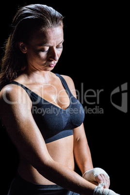 Sexy female athlete tying bandage on hand