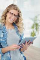 Portrait of happy woman wearing eyeglasses while using digital t