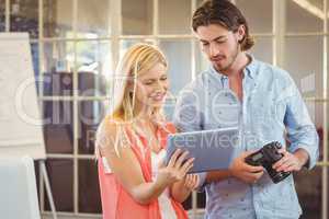 Businesswoman showing something to male colleague on digital tab