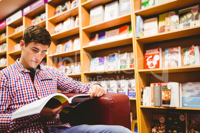 Concentrated young man reading book in library