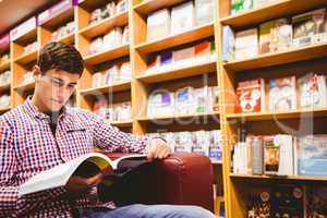 Concentrated young man reading book in library