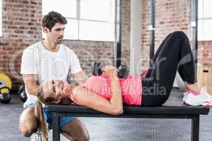 Fit woman lifting dumbbells with trainer