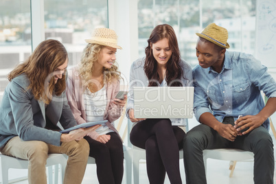 Smiling business people using technology while discussing