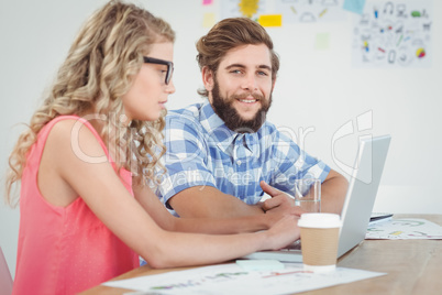 Portrait of smiling man with woman working on laptop