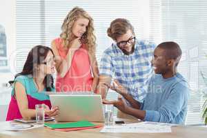 Man gesturing in front of coworkers in creative office