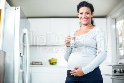 Portrait of happy pregnant woman holding a glass of water
