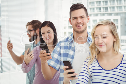 Smiling business professionals using smartphones while standing