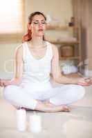 Full length of woman in yoga pose while meditating on floor
