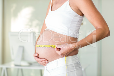 Midsection of woman measuring belly