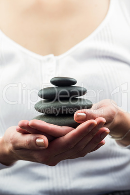 Mid section of woman holding black pebbles