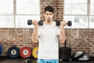 Portrait of muscular man lifting dumbbells