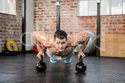 Portrait of man doing push ups with kettlebell