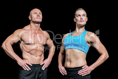 Muscular man and woman with hand on hip