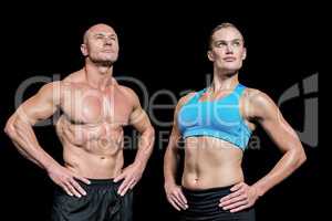 Muscular man and woman with hand on hip