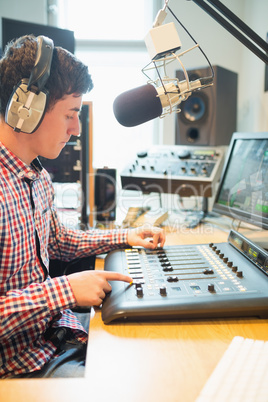 Radio host wearing headphones operating sound mixer