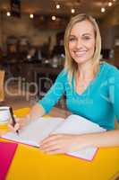 Portrait of happy young woman writing on book