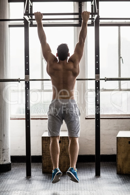 Muscular man lifting himself up and down