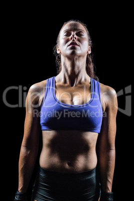 Fit woman meditating against black background
