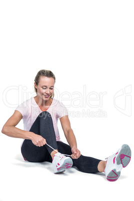 Fit woman smiling while tying shoelace