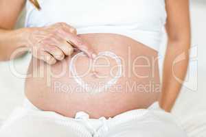 Midsection of pregnant belly with heart lotion