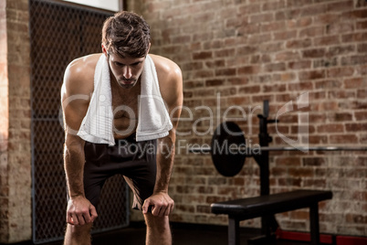 Muscular man with hands on knees