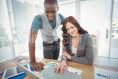 Smiling businesswoman working on laptop with coworker