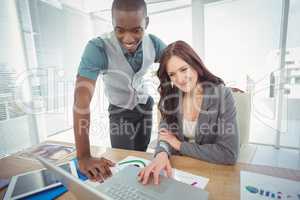 Smiling businesswoman working on laptop with coworker