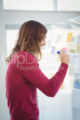 Hipster writing on adhesive note stuck on glass
