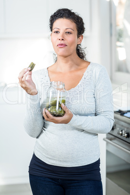 Attractive pregnant woman eating a pickle
