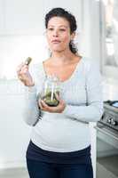 Attractive pregnant woman eating a pickle