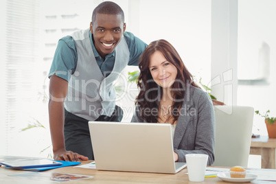 Portrait of smiling businesswoman working on laptop with coworke