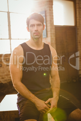 Muscular man sitting on plyo box